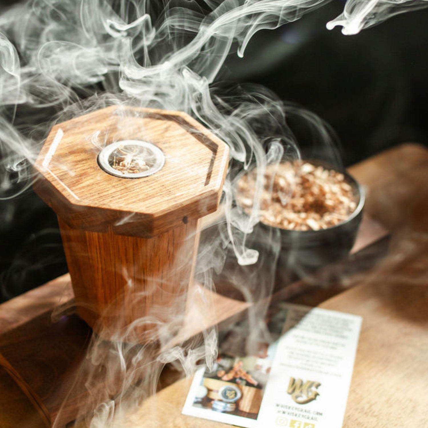 Wooden Smoker on top of The Whiskey Grail with smoke on a wooden surface